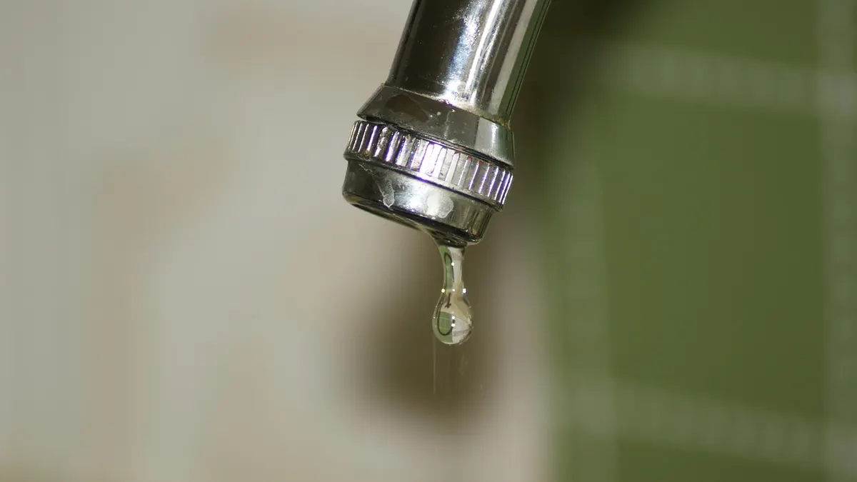 Torneira de metal com gota de água pingando