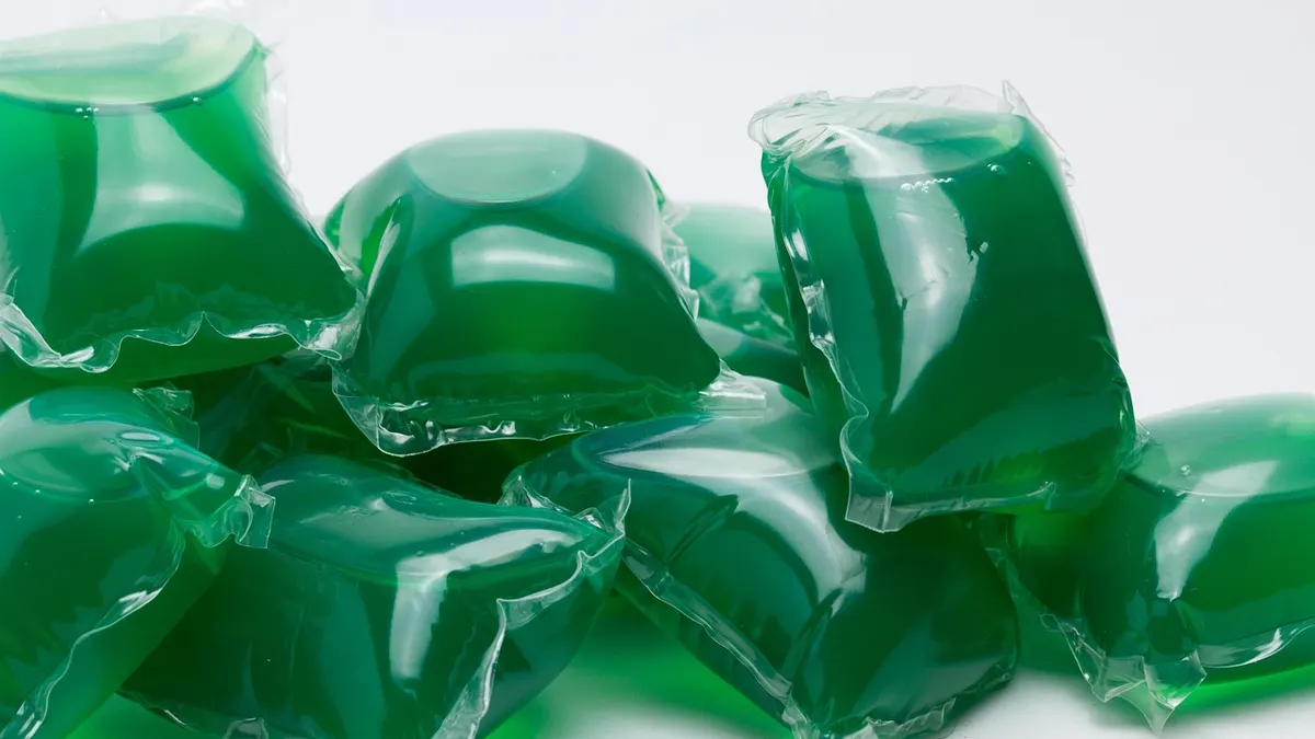 Cápsulas verdes de detergente para lavar roupa sobre fundo branco
